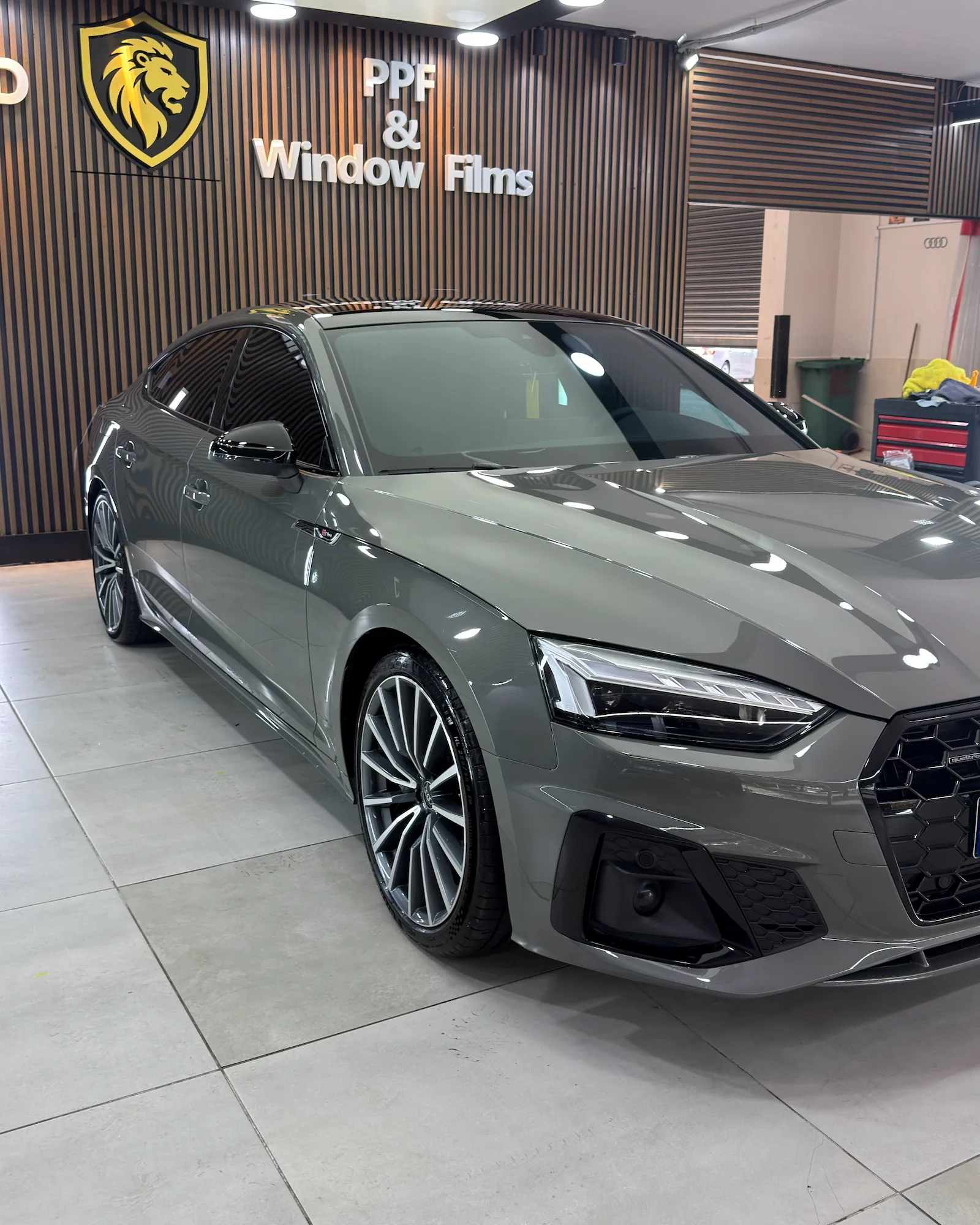 Uygulama merkezinde gri Audi A5 Sportback, kaputunda ışık yansımaları