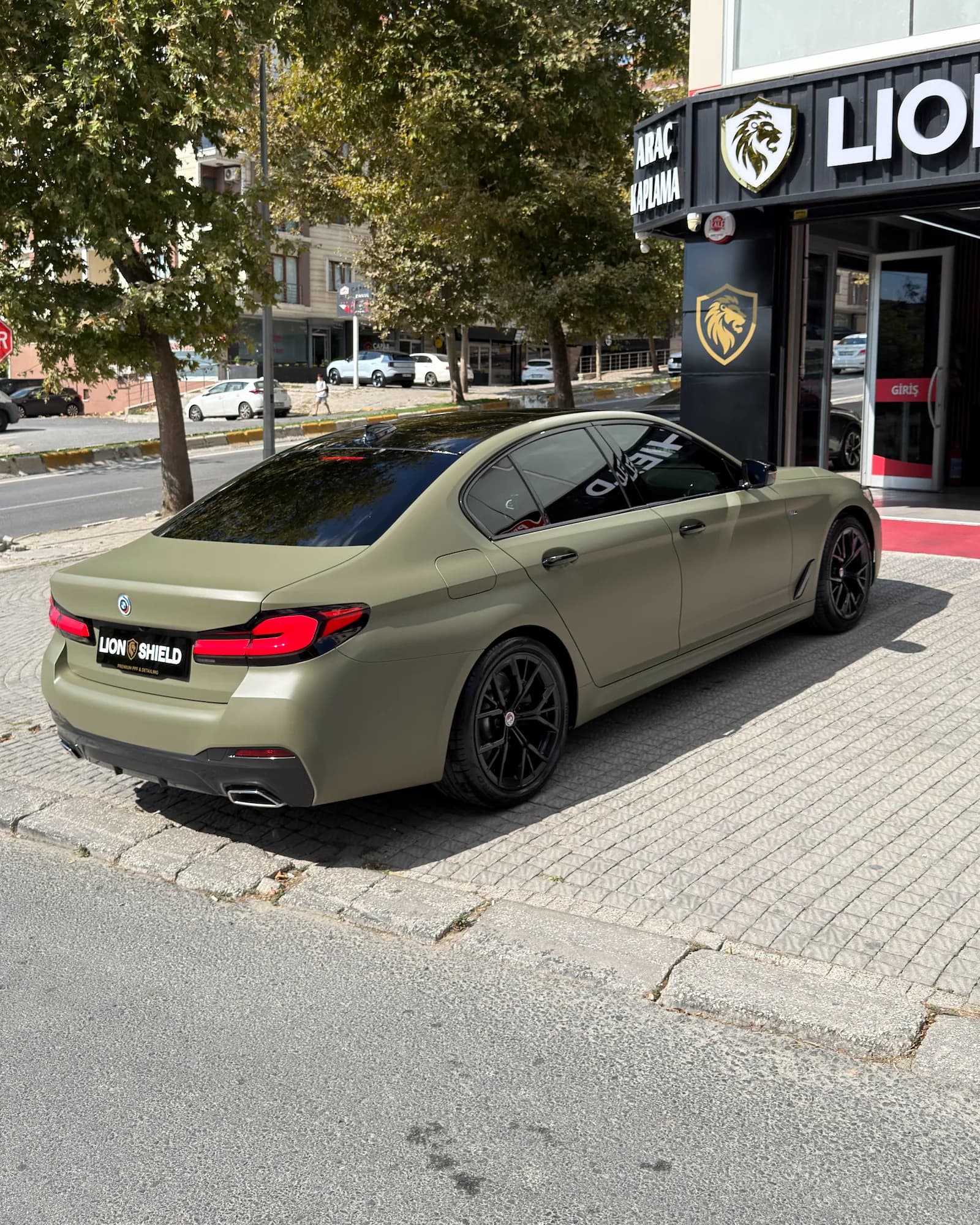 Mat haki BMW 5 Serisi’nin arka çaprazdan görünümü, camlarına koyu film uygulanmış