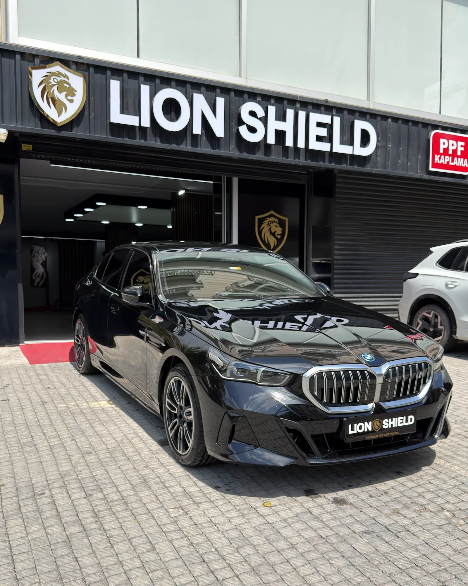 Uygulama merkezinin girişinde siyah BMW 5 Serisi’nin ön çaprazdan görünümü