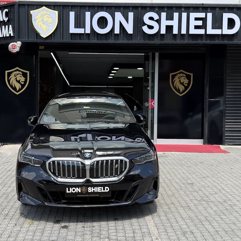 Uygulama merkezinin girişinde siyah BMW 5 Serisi’nin önden görünümü