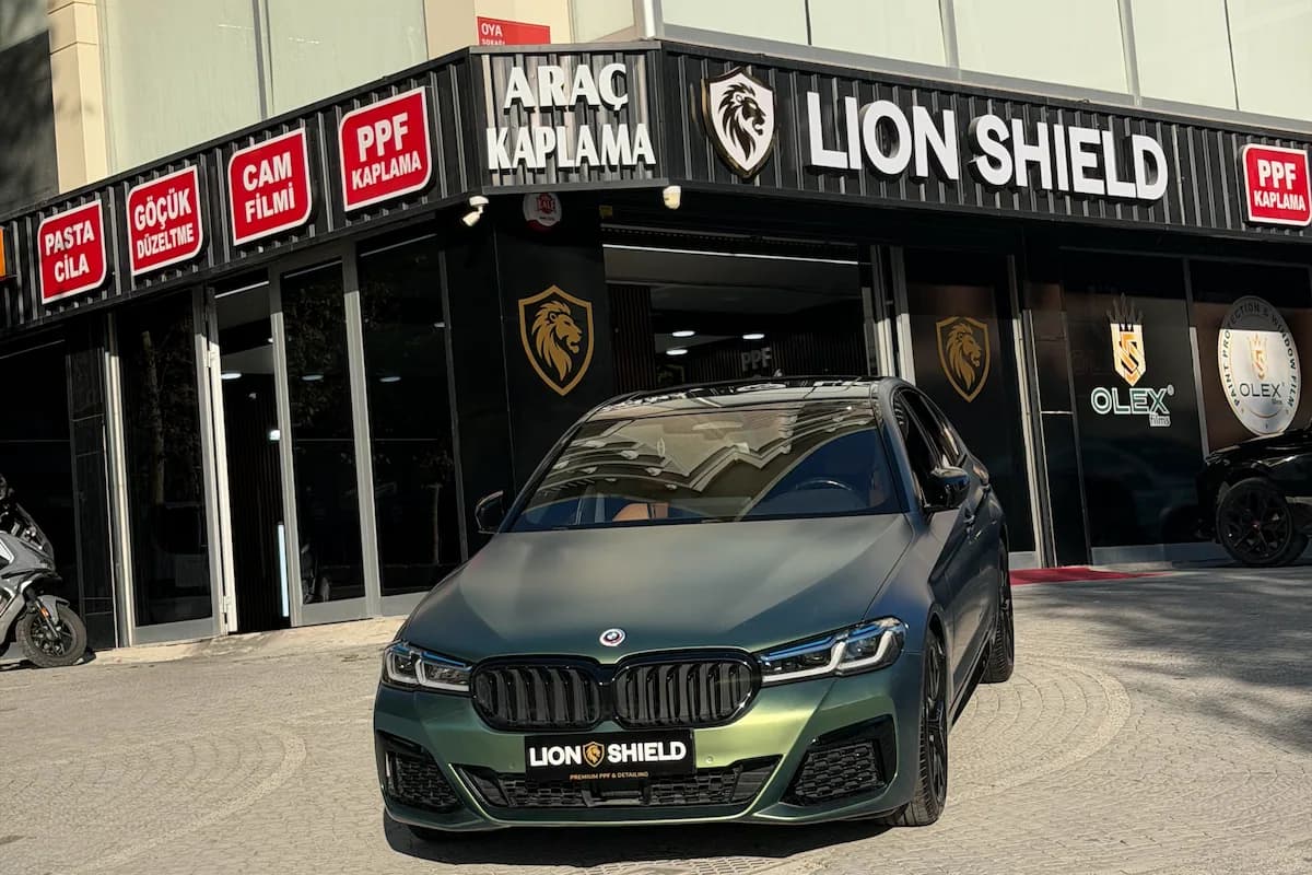 Lion Shield uygulama merkezinin girişi ve önünde duran mat yeşil BMW 5 Serisi