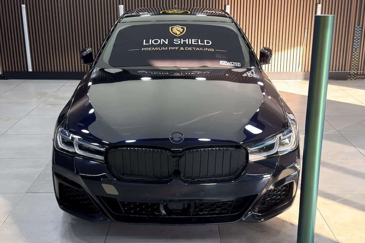 Ön ızgarası sökülmüş, ön camı örtülmüş BMW ve yanında duran film rulosu